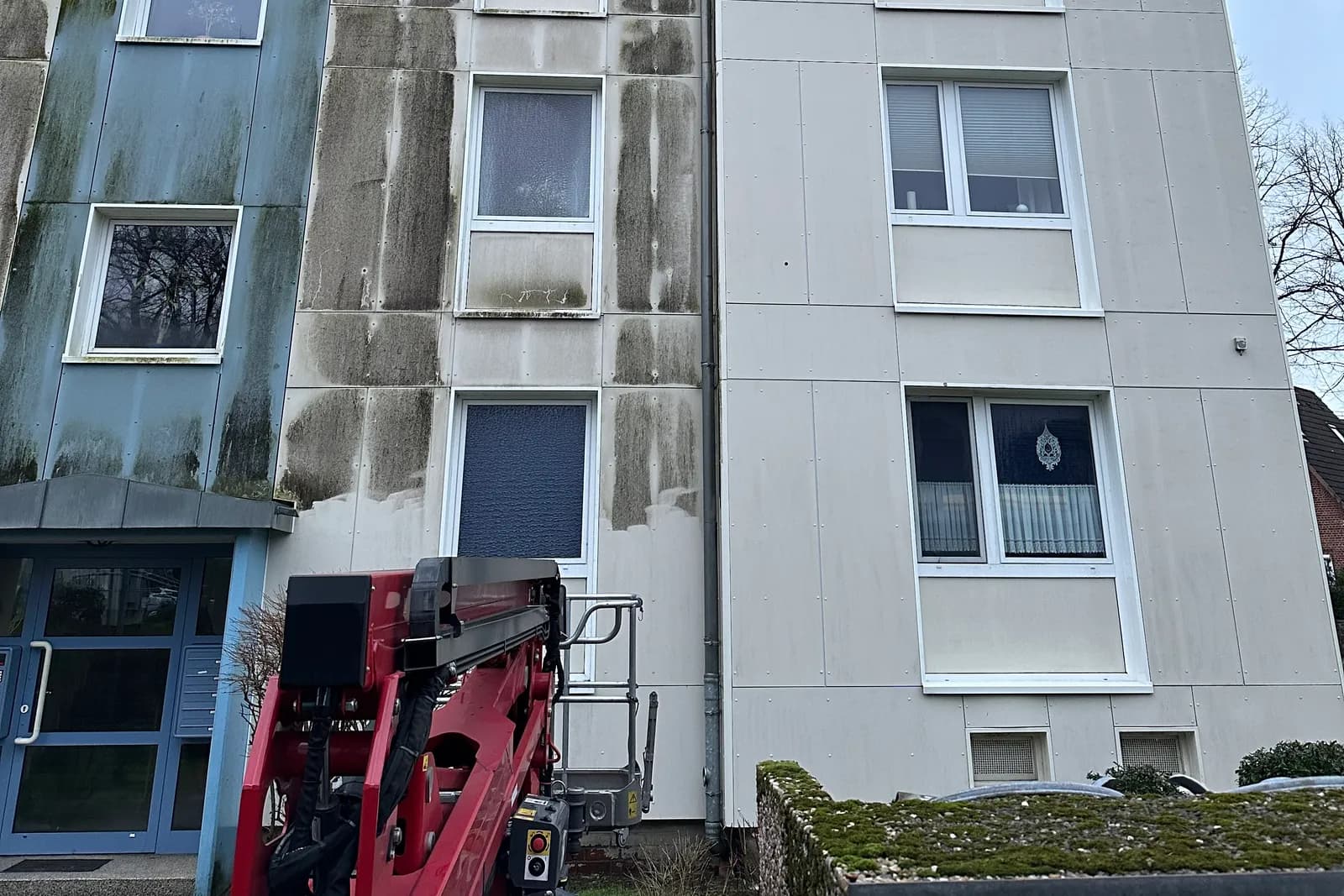 Mehrfamilienhaus mit deutlichen Algenspuren an der Fassade vor der Reinigung
