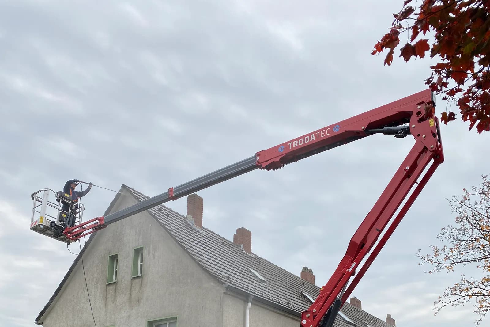 Rote Raupen-Arbeitsbühne von TRODATEC vor einem Reihenhaus im Einsatz