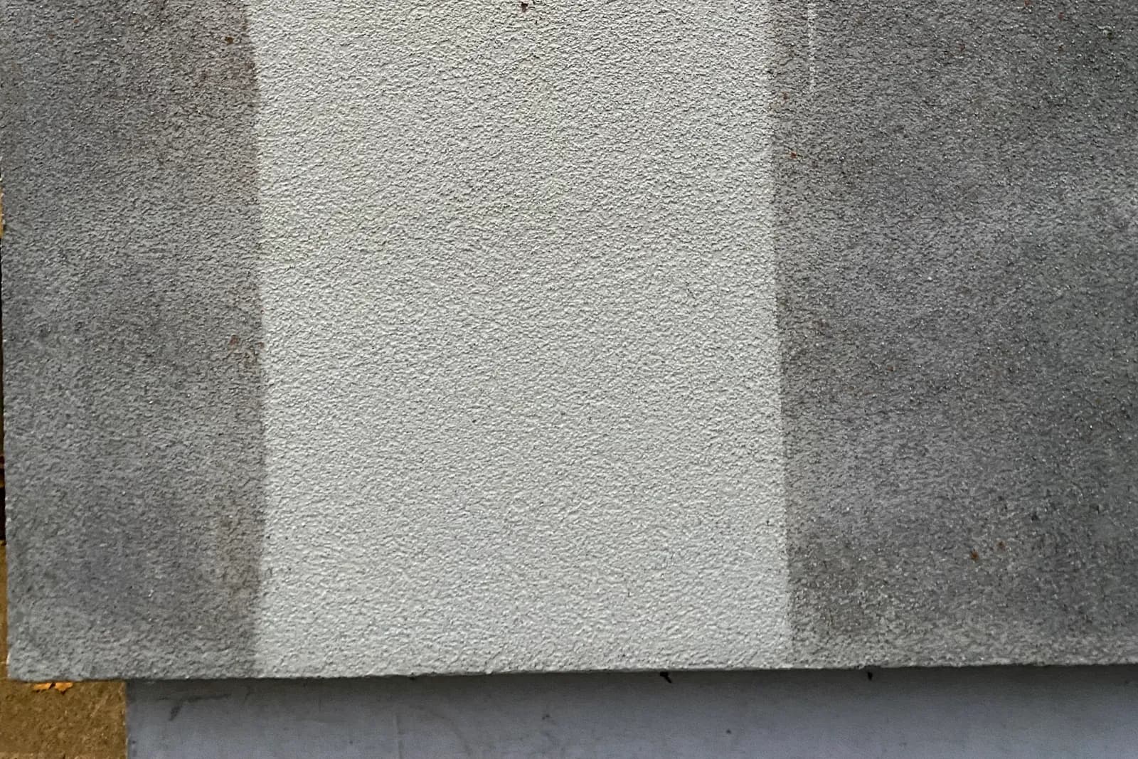 Gereinigte Probefläche auf einer Putzfassade, direkt daneben die unbehandelte Wand