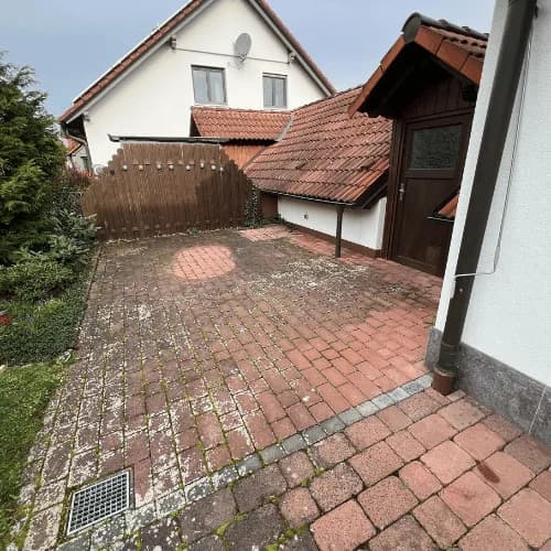 Gepflasterte Hofeinfahrt mit Moos und Grünbelag vor der Steinreinigung